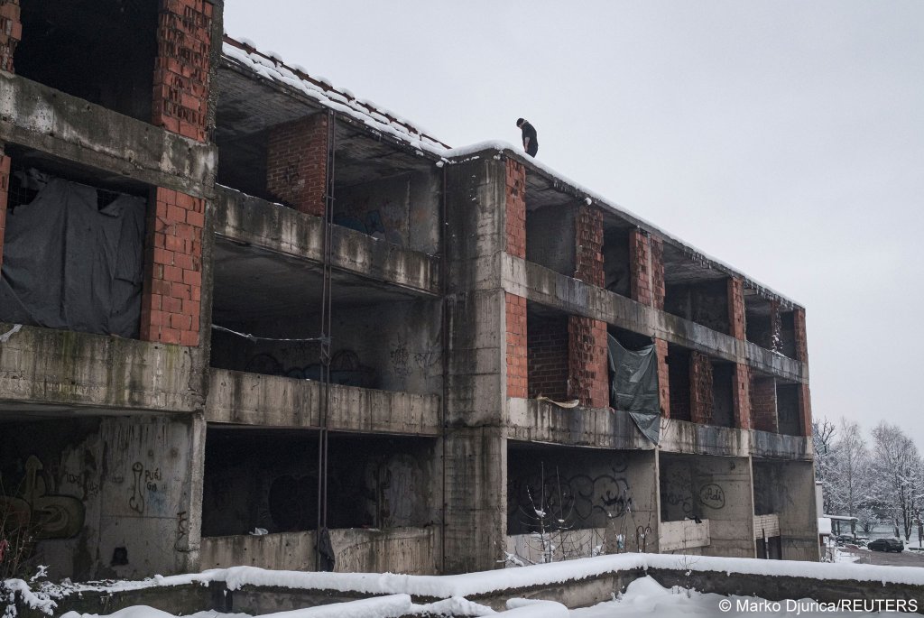 A migrant stands on the roof of a building on January 11, 2021 as hundreds of them are taking shelter in abandoned buildings in the northwestern town of Bihac in Bosnia and Herzegovina | Photo: Marko Djurica/Reuters
