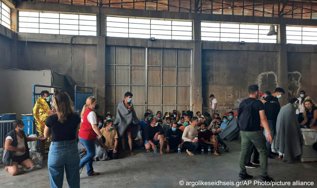 Survivors of a shipwreck sit in a warehouse at the port of Kalamata, about 240 kilometers southwest of Athens, on Wednesday, June 14, 2023 | Photo: AP/picture-alliance