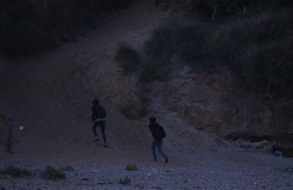 Des migrants courent se cacher dans les dunes de la Slack, le 8 septembre 2021. Crédit : Mehdi Chebil pour InfoMigrants