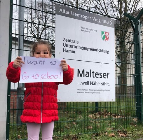 One of Maher's daughters holds up a sign asking to be allowed to attend school | Photo: Private
