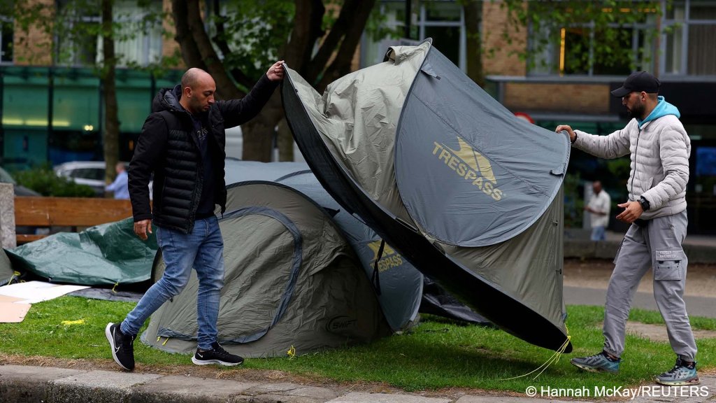 Asylum seekers move a tent at a makeshift camp, set up by migrants, along the banks of the Grand Canal, in Dublin, Ireland, on May 22, 2024 | Photo: Reuters/Hannah McKay