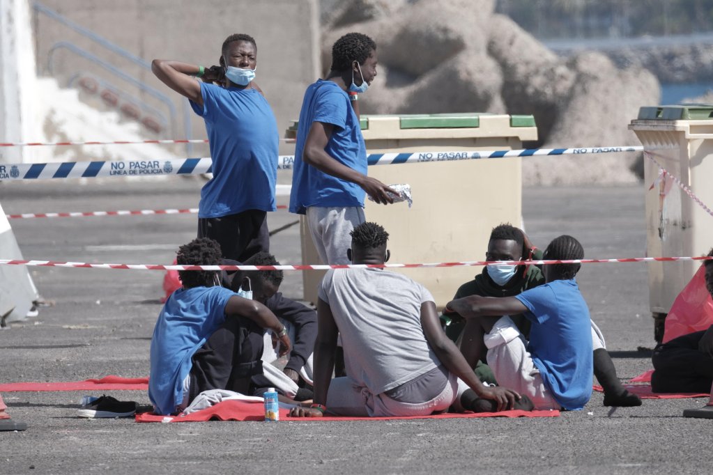 Migrants sit at the docks in Arguineguin, Canary Islands, Spain, waiting to be tested for COVID-19 prior to be put under quarantine | Photo: EPA/ANGEL MEDINA