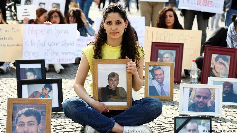 Syrian woman Sedra Alshehabi with a picture of her missing father at a Berlin protest | Photo: Christian Mang/REUTERS