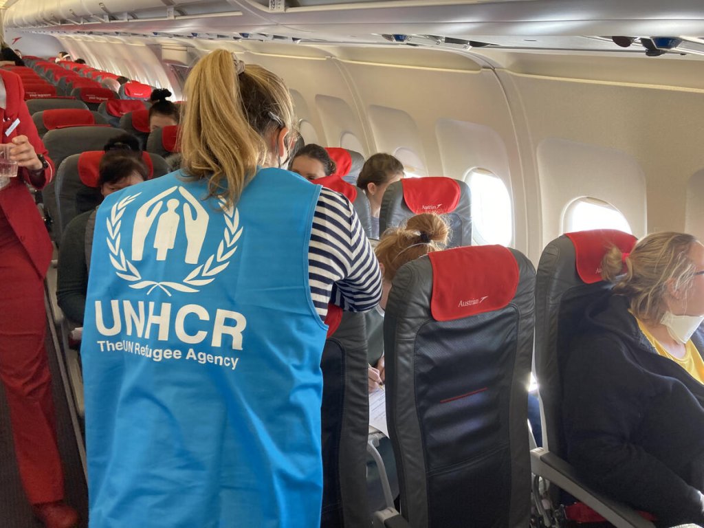 A UNHCR staff member helps refugees from Ukraine, including families with children and people with special needs, to board a plane bound for Vienna | Photo: UNHCR