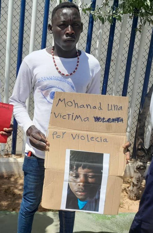 Sur la photo de la pancarte, Mohamad a le visage tuméfié après avoir été roué de coups, le mercredi 25 mai au CETI. Crédit : DR