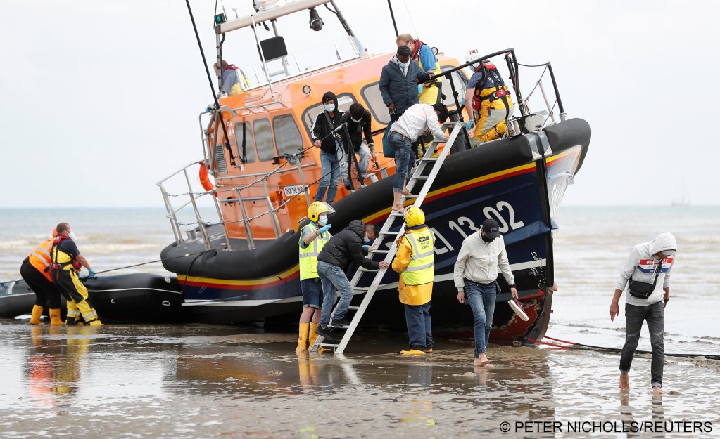 Migrants climb off an RNLI lifeboat on the beach at Dungeness after being rescued at sea | Photo: Peter Nicholls / Reuters