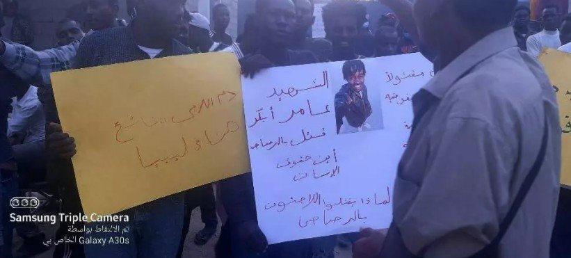Des migrants brandissant des pancartes réclamant justice pour le meutre du jeune Soudanais, Amer Baker, devant le bureau du HCR. Crédit : Tarik Lamloum / Facebook
