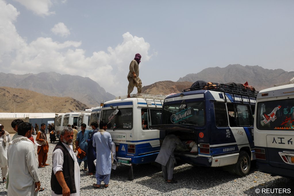 A displaced Afghan man stands on top of a van at a cash aid distribution center for displaced people in Kabul, Afghanistan on July 28, 2022 | Photo: Ali Khara/Reuters