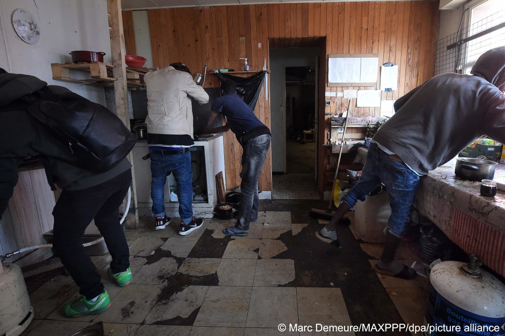 Migrants clean up the kitchen at the squat in Calais | Photo: Marc Demeure / MAXPPP/ dpa / picture alliance