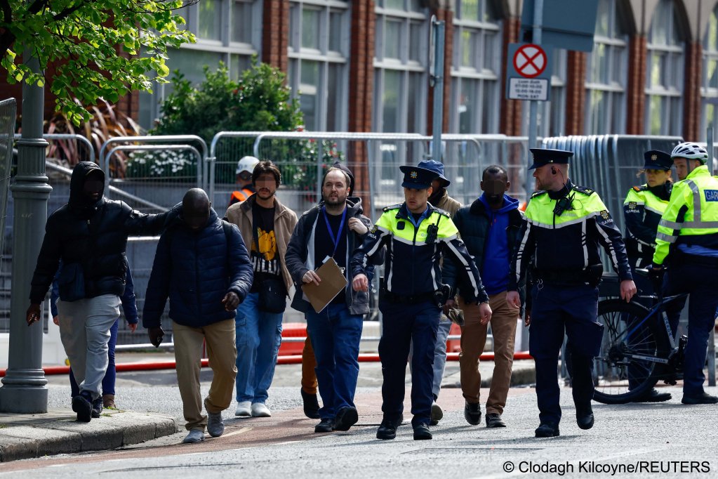 People believed to be asylum seekers are escorted away, as Irish police (Garda) start to dismantle the tent camp outside the IPO in Dublin | Photo: Clodagh Kilcoyne / Reuters
