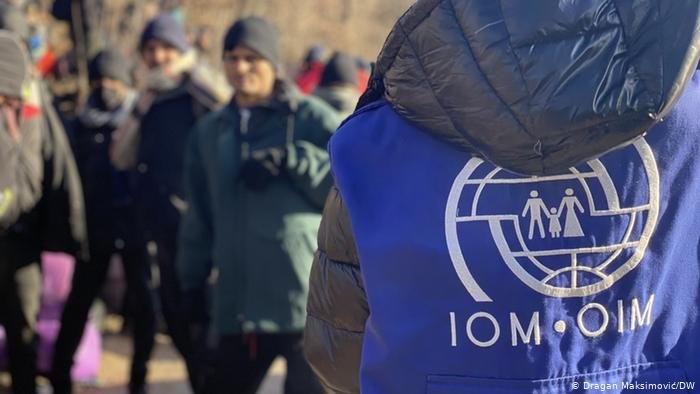 موظف من المنظمة الدولية للهجرة ومهاجرون في 30 ديسمبر 2020 بالقرب من مخيم "ليبا"