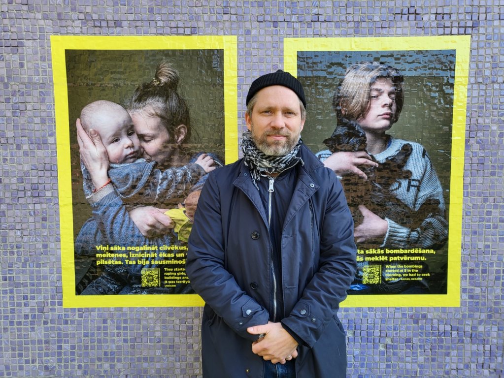 Danish photographer Martin Thaulow standing in front of portraits of Ukrainian refugees in Riga | Photo: Benjamin Bathke/InfoMigrants