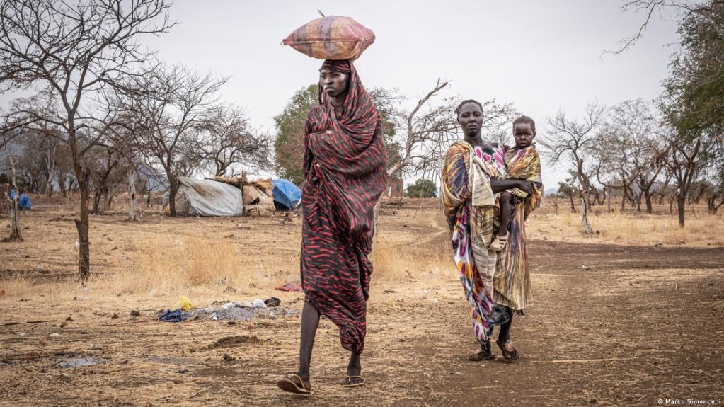 Women carrying sacks of grain they received as they return to their shelters in the Nuba Mountains | Photo: Marco Simoncelli