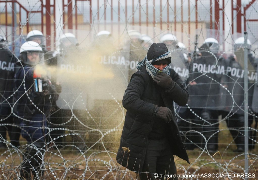 Polish serviceman sprays tear gas during clashes between migrants and Polish border guards at the Belarus-Poland border near Grodno, Belarus, on Tuesday, Nov. 16, 2021 | Photo: Leonid Shcheglov/AP/picture-alliance