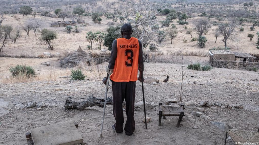Hassan Koko stands on crutches overlooking the landscape from his village near Gidel in South Kordofan | Photo: Marco Simoncelli