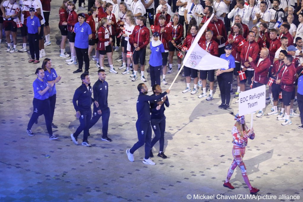 EOC Refugee Team i jej flagowcy Cindy Winner Djankeu Ngamba (boks) i Kasra Mehdipournejad (taekwondo) wchodzą na stadion podczas parady sportowców podczas ceremonii otwarcia Igrzysk Europejskich 2023 w Krakowie, Polska, 21 czerwca 2023 r. |  Zdjęcie: Mickael Chavet/Zuma/picture-alliance 