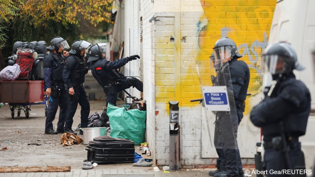 Police kick down a door at the abandoned school | Photo: Albert Gea / Reuters