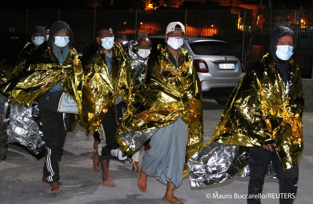 Migrants walk, wrapped in emergency thermal blankets, after arriving by the hundreds on the southern island of Lampedusa, Italy May 9, 2021 | Photo: REUTERS/Mauro Buccarello