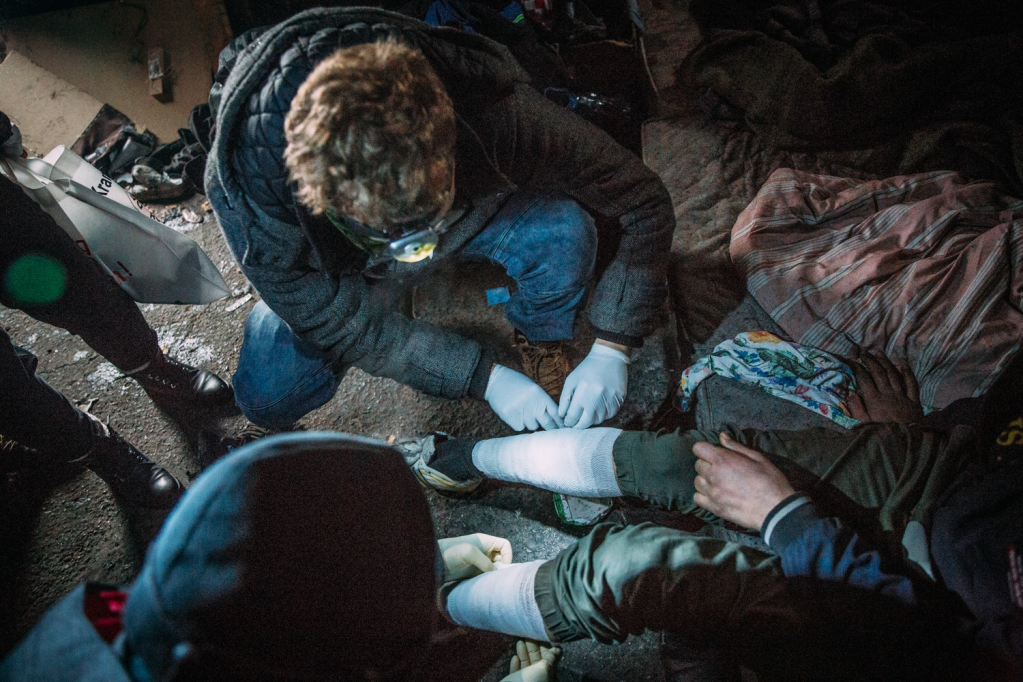 Member of the "Armut und Gesundheit in Deutschland" team putting a bandage on a migrant in an abandoned building in Bihać, Bosnia in January 2021 | Photo: Alea Horst