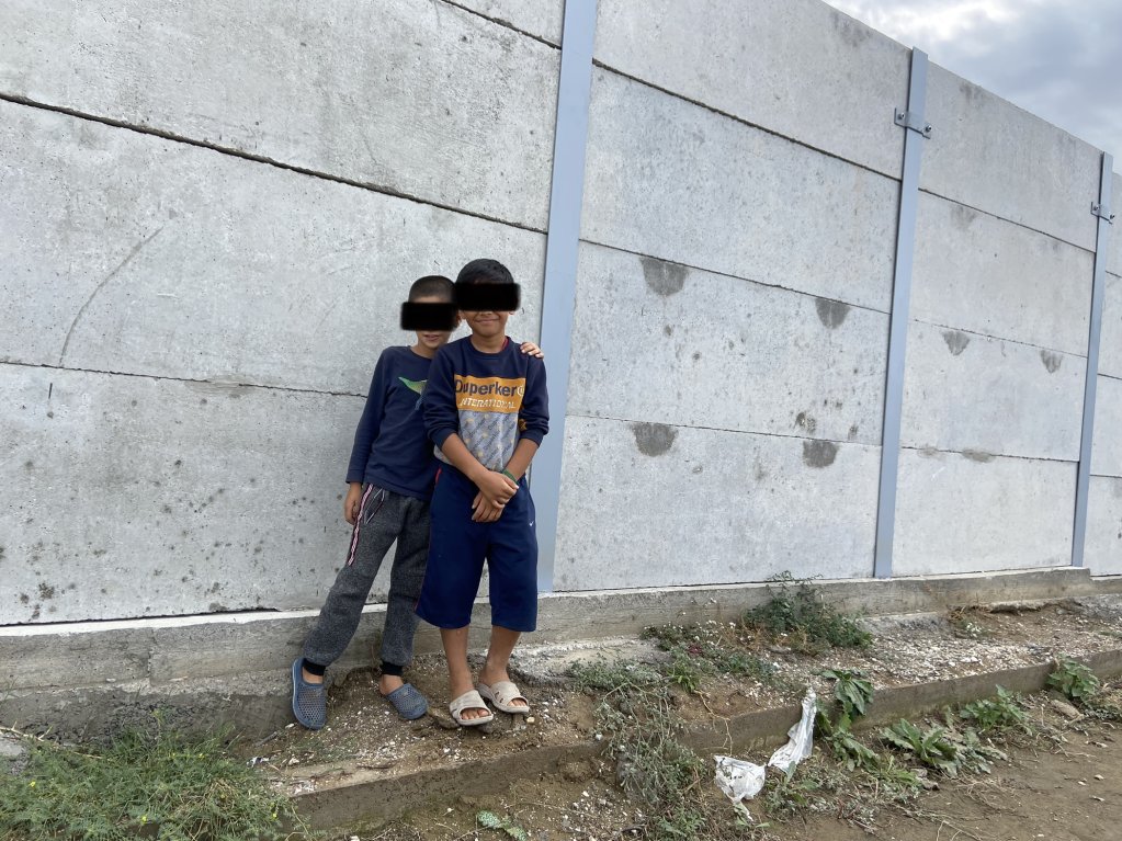Deux enfants afghans devant le mur de clôture de Nea Kavala, en Grèce. Crédit : InfoMigrants