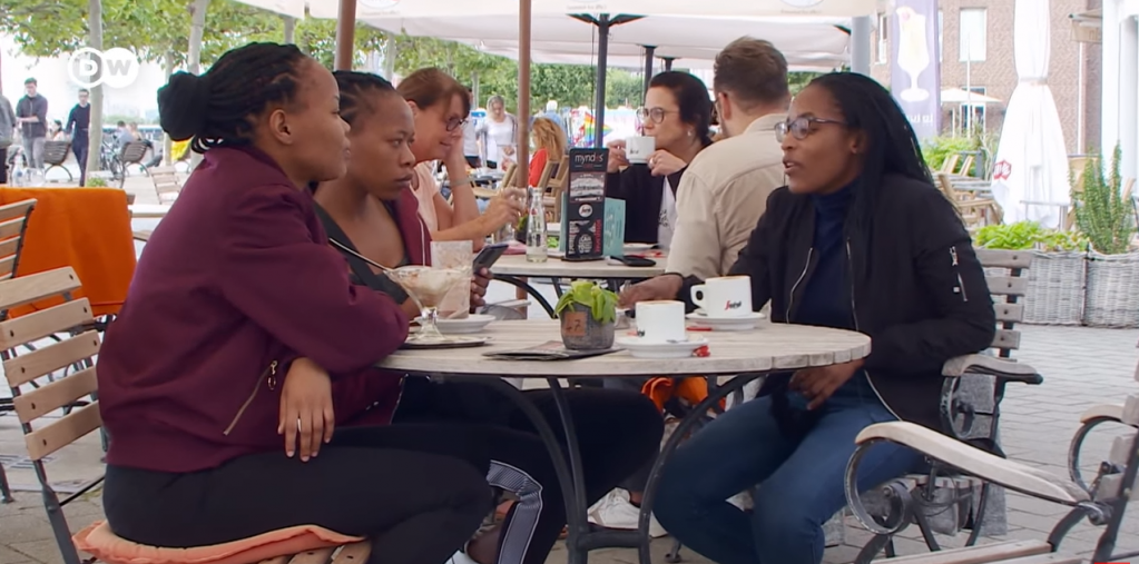 Iyaloo et deux de ses collègues sur une terrasse de Düsseldorf | Source : Capture d’écran du documentaire de la DW