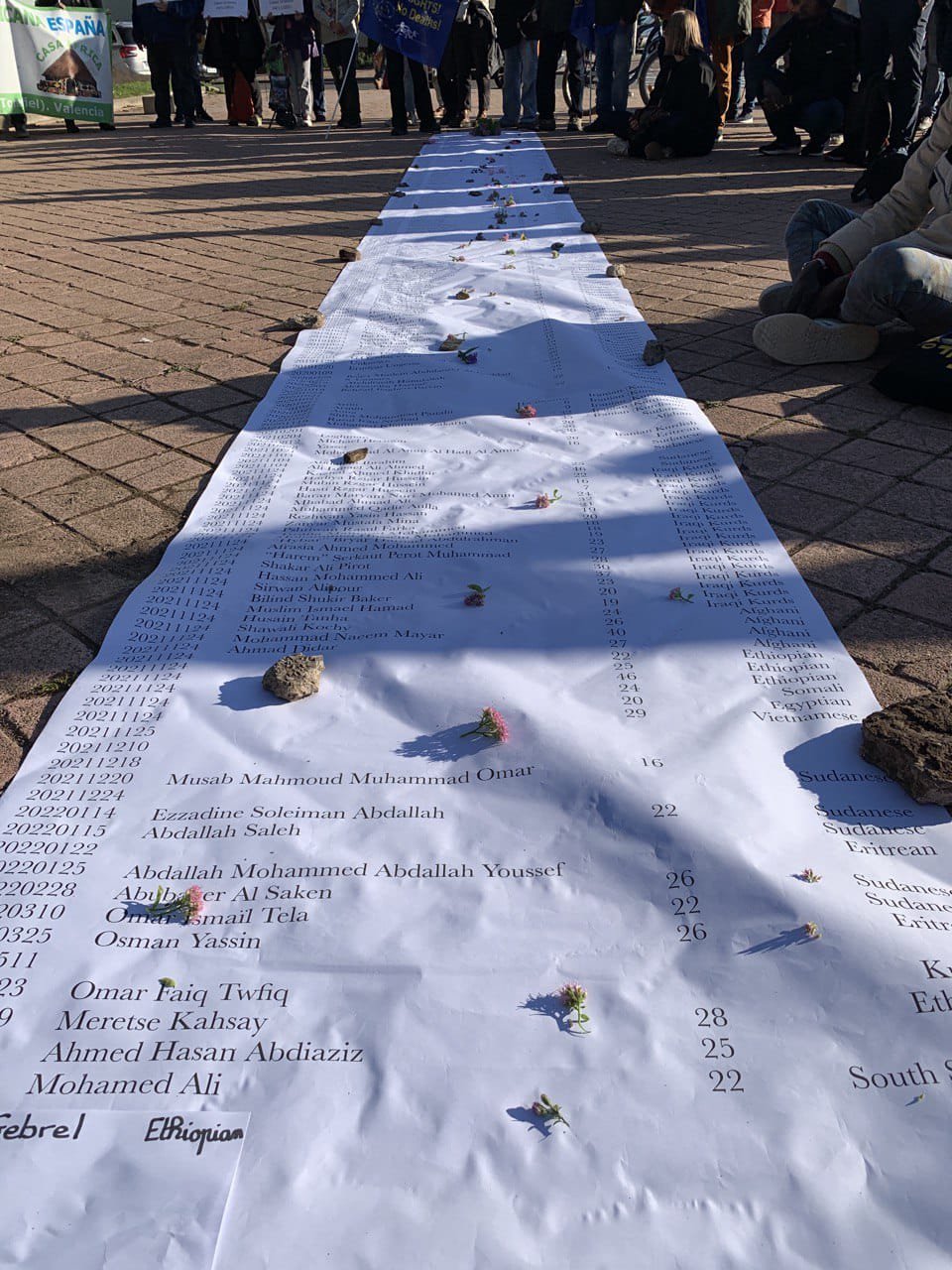 Les manifestants se recueillent autour d'une banderole avec des noms de migrants décédés lors de leur trajet vers l'Europe. Crédit : Caravana Abriendo Fronteras