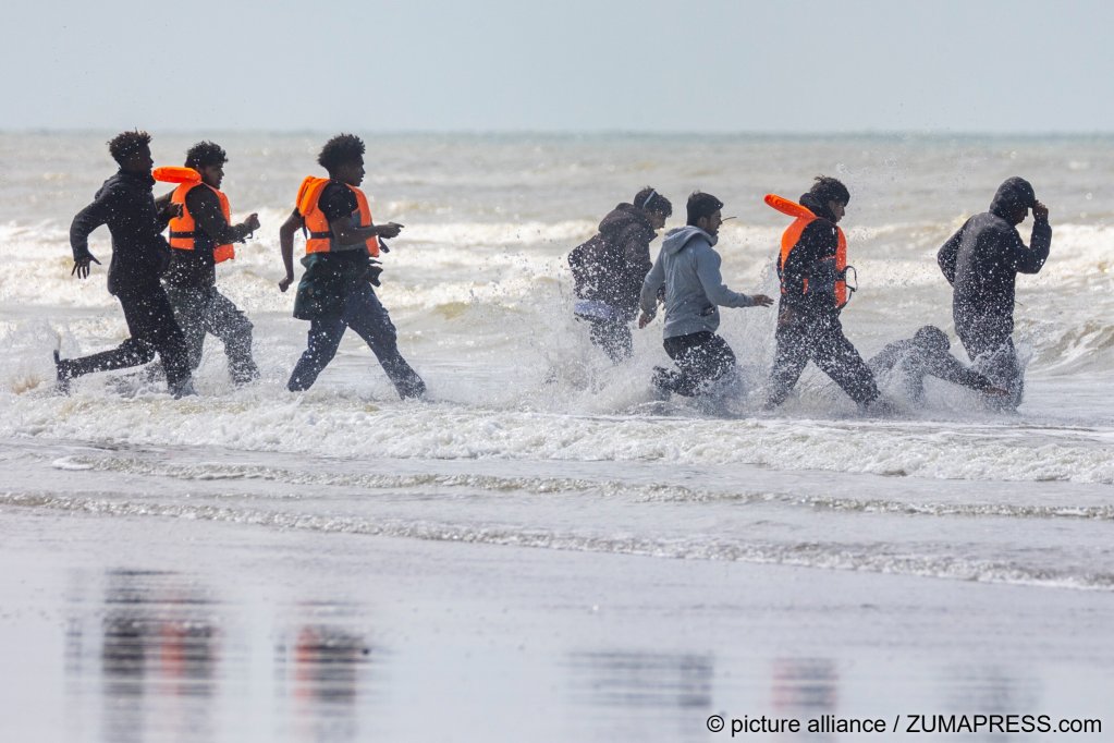 Migrants run along the beach at Hardelot in an attempt to board an inflatable boat waiting off shore | Photo: Marcin Nowak / Zuma press wire / picture alliance